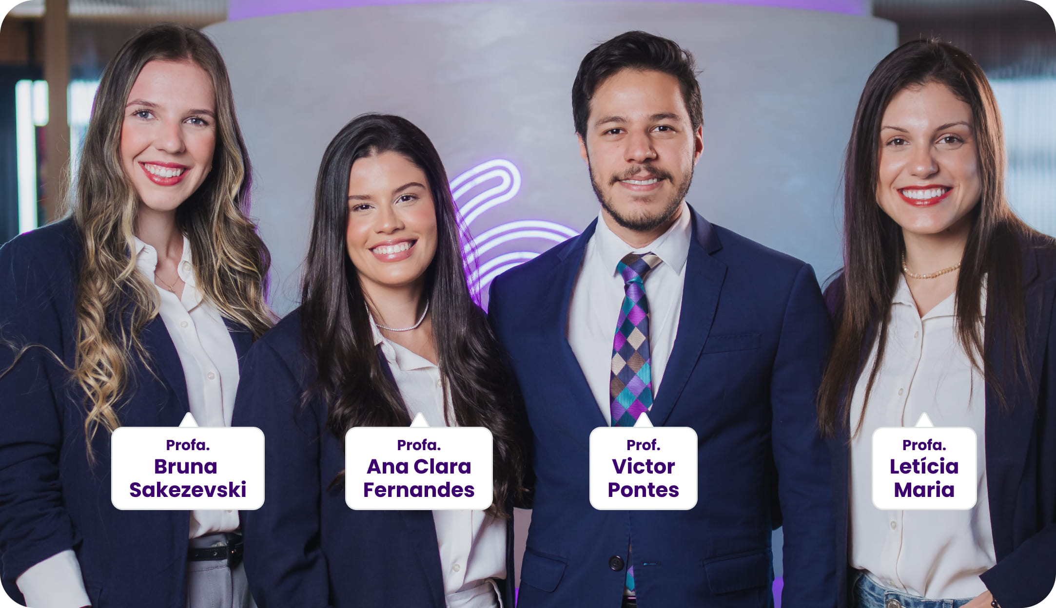 Quatro professores posam sorrindo para a foto. Da esquerda para a direita: Profa. Bruna Sakezevski, Profa. Ana Clara Fernandes, Prof. Victor Pontes e Profa. Letícia Maria. Todos estão vestidos formalmente com blazer azul marinho e camisa branca. Ao fundo, um ambiente moderno com iluminação roxa.
